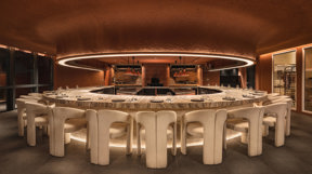 Bar Kar interior. A circular restaurant table with chairs in a warm toned room.